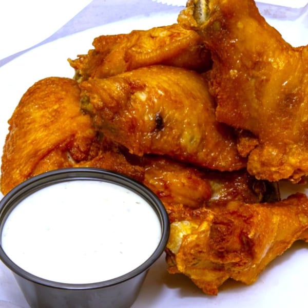 Nozzleman pizza's crispy golden-brown chicken wings with a side of creamy ranch dipping sauce.