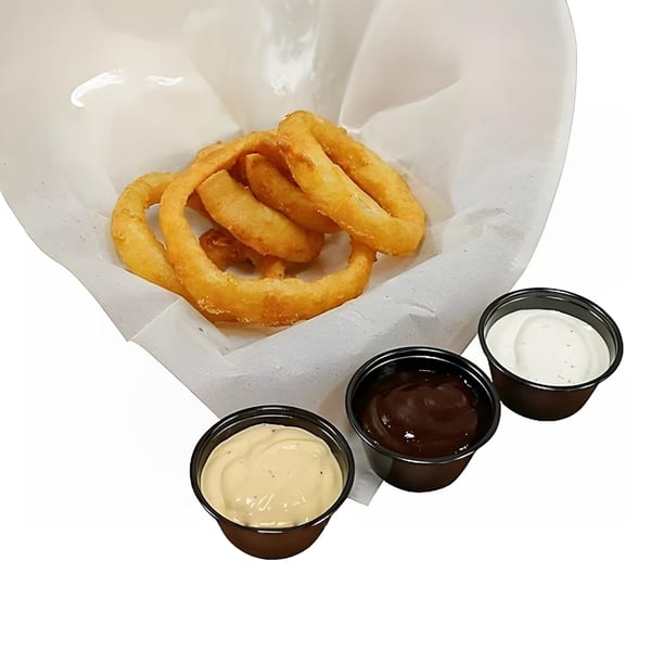 Golden-brown onion rings in a white paper-lined basket, with three dipping sauces on the side.